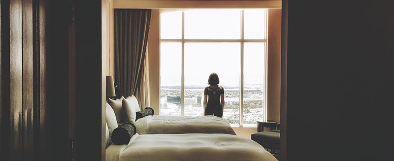 Woman looking out window of hotel room - Temple Inn and Suites